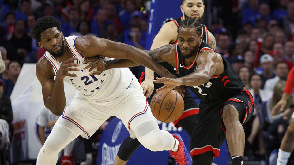 Toronto Raptors' Kawhi Leonard, right, reaches for the ball as he holds off Philadelphia 76ers' Joel Embiid. (AP Photo/Chris Szagola)