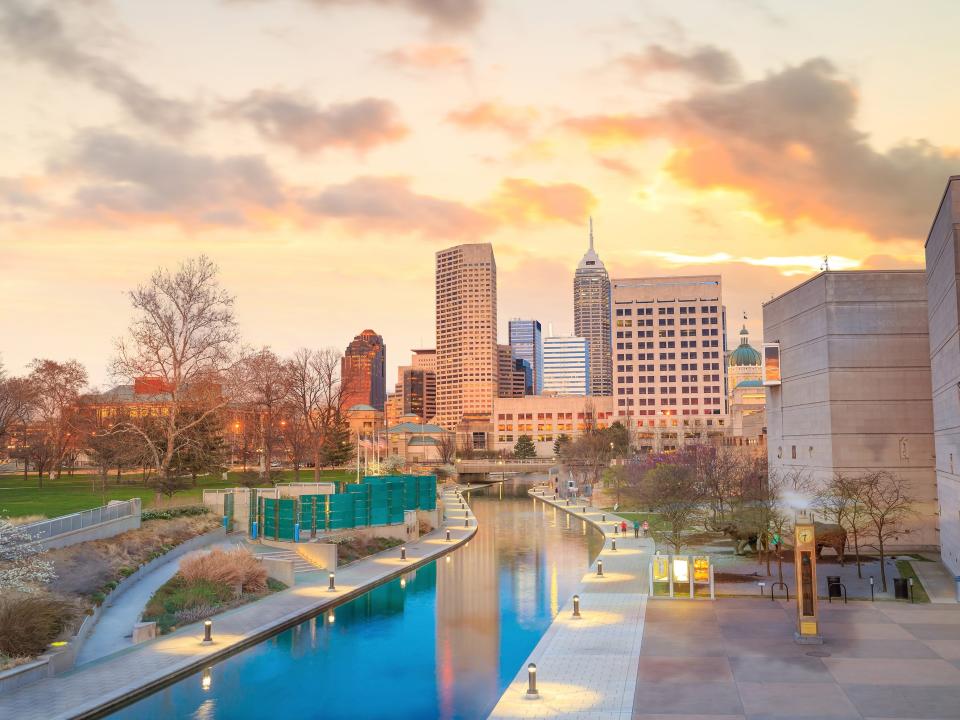 The Indianapolis skyline next to a body of water at sunset.