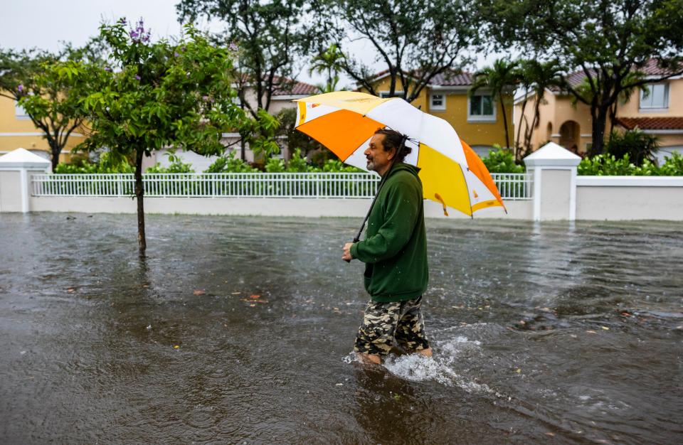 Drew Donner walks down Taft Street as heavy rain floods the nearby neighborhood n Wednesday, June 12, 2024, in Hollywood, Fla. The annual rainy season has arrived with a wallop in much of Florida, where a disorganized disturbance of tropical weather from the Gulf of Mexico has caused street flooding and triggered tornado watches but so far has not caused major damage or injuries. (Matias J. Ocner/Miami Herald via AP)