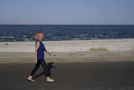 Carlene Ness walks on a road along the Salton Sea in Desert Shores, Calif., Wednesday, July 14, 2021. Ness moved to the area in 1999 with her husband, who has since passed away. They were attracted by the abundant wildlife and the boating docks along the shore, which have since dried up. Longtime residents like Ness miss when eared grebes, cormorants and white and brown pelicans were more abundant. “The noise was awesome,” she said. “That’s what everybody bought for, and we have to fight for it.” (AP Photo/Marcio Jose Sanchez)