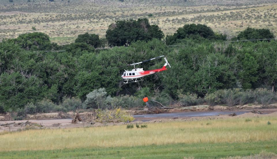 A helicopter crew collects water from Fountain Creek north of Pueblo during a firefighting operation on the creek east of Interstate 25 on Tuesday, July 18, 2023.