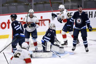 Florida Panthers' Carter Verhaeghe (23) celebrates his goal on Winnipeg Jets goaltender Connor Hellebuyck (37) with Maxim Mamin (98) during the second period of an NHL hockey game, Tuesday, Jan. 25, 2022 in Winnipeg, Manitoba. (Fred Greenslade/The Canadian Press via AP)