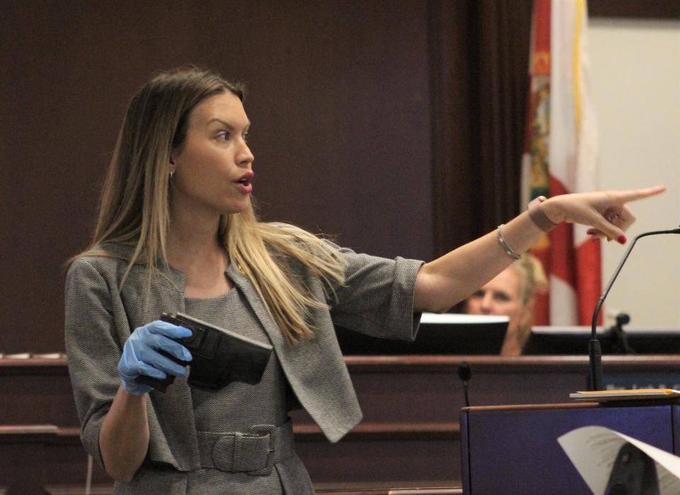 Assistant State Attorney Sarah Thomas holds a holstered .40-caliber Glock as she points toward Damon Kemp, who is accused of using the gun to kill two people.