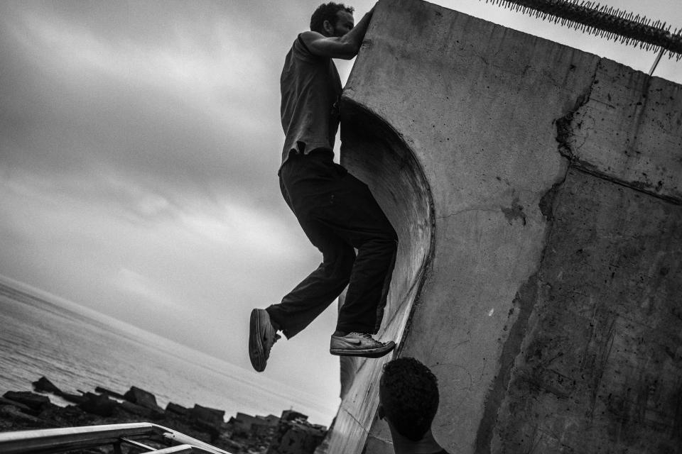 A young migrant tries to jump the wall of the port of Melilla in 2014. (Photo: José Colón/MeMo for Yahoo News)