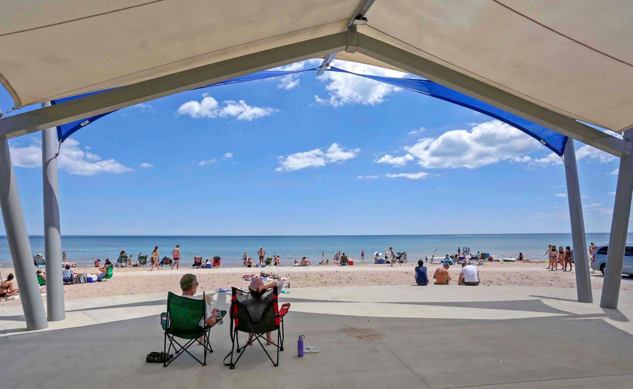 FILE - A couple watches the action under a canopy at Neshotah Beach on Thursday, June 25, 2020, in Two Rivers.