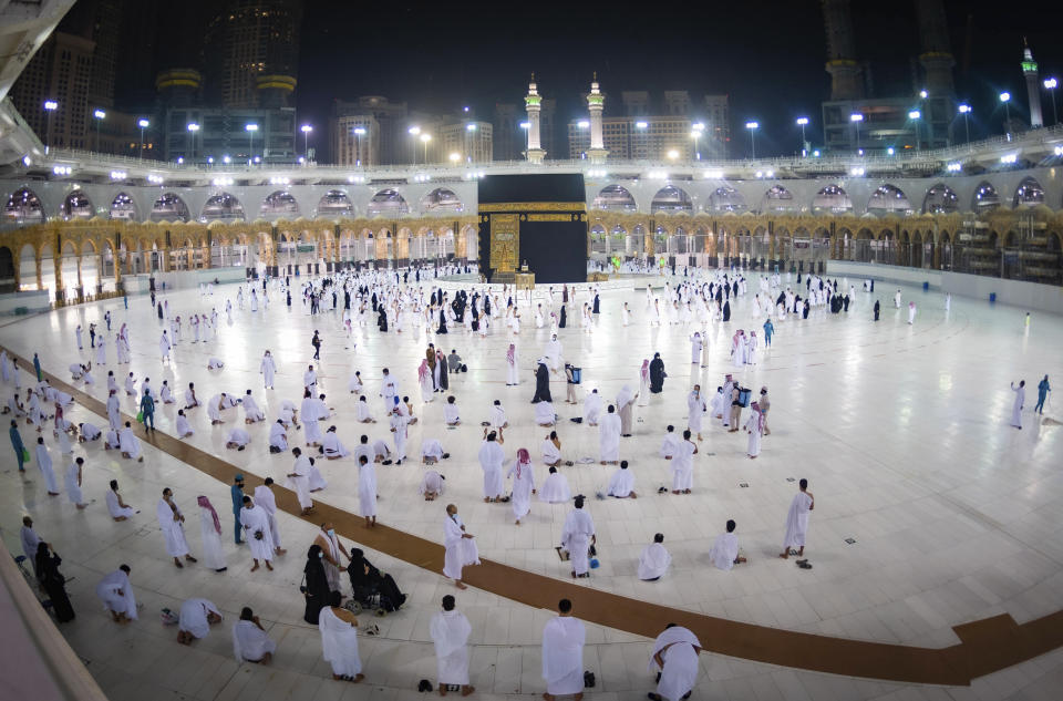 CLARIFIES THAT THE UMRAH PILGRIMAGE CAN BE UNDERTAKEN AT ANY TIME OF THE YEAR -- In this photo released by Saudi Ministry of Hajj and Umrah, Muslims practice social distancing while praying around the Kaaba, the cubic building at the Grand Mosque during the first day umrah pilgrimages were allowed to restart, in the Muslim holy city of Mecca, Saudi Arabia, Sunday, Oct. 4, 2020. The umrah pilgrimage, or smaller pilgrimage, can be undertaken at any time of the year. A very small, limited number of people donning the white terrycloth garment symbolic of the Muslim pilgrimage circled Islam's holiest site in Mecca on Sunday after Saudi Arabia lifted coronavirus restrictions that had been in place for months. (Saudi Ministry of Hajj and Umrah via AP)