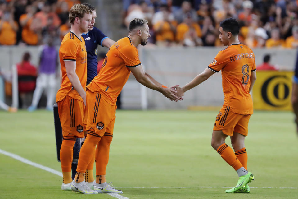 Houston Dynamo forward Thor Ulfarsson, left, looks on as midfielder Hector Herrera, center, shakes hands with Memo Rodriguez (8) as Rodriguez leaves the pitch as Ulfarsson and Herrera are substituted into an MLS soccer match during the second half against FC Dallas, Saturday, July 9, 2022, in Houston. (AP Photo/Michael Wyke)