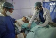 FILE - In this June 14, 2020, file photo, medical workers attend to a COVID-19 patient in an intensive care unit at a hospital in Sanaa, Yemen. A new snapshot of the frantic global response to the coronavirus pandemic shows some of the world's largest government donors of humanitarian assistance are buckling under the strain and overall aid commitments have dropped by a third from the same period last year. (AP Photo/Hani Mohammed, File)