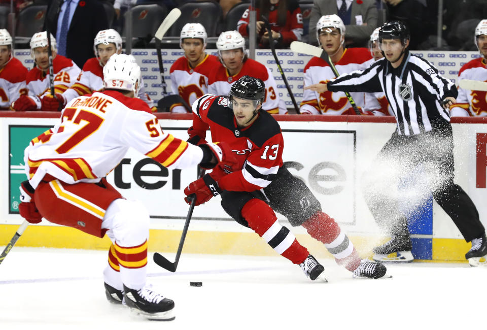 New Jersey Devils center Nico Hischier (13) controls the puck against Calgary Flames defenseman Nick DeSimone (57) during the first period of an NHL hockey game, Tuesday, Nov. 8, 2022, in Newark, N.J. (AP Photo/Noah K. Murray)