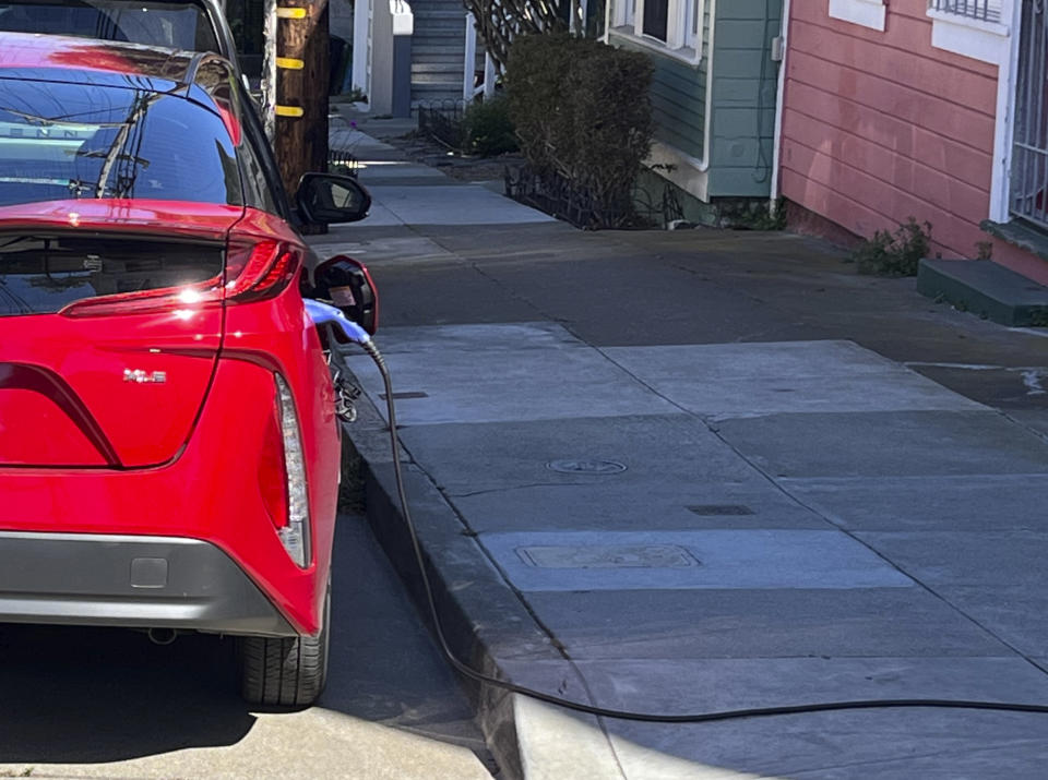 A charging cord for an electric vehicle is seen strung across a public sidewalk in San Francisco on Sept. 23, 2022. The great transition to electric vehicles is underway for homeowners who can charge their cars in a private garage, but for millions of renters access to charging remains a significant barrier. Renters have resorted to stringing extension cords across public sidewalks and erecting private chargers in public rights-of-way as cities try to install more public charging to meet the demand. (AP Photo/Haven Daley)