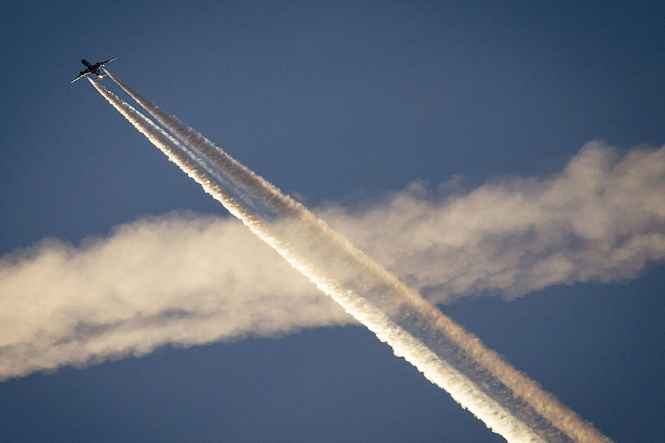 FILE - An aircraft crosses the vapor trails of another plane over Frankfurt, Germany, on April 19, 2018. On Friday, Oct. 21, 2022, The Associated Press reported on stories circulating online incorrectly claiming that a CNBC story on research into technology to combat climate change admitted that “chemtrails” are real. (AP Photo/Michael Probst, File)