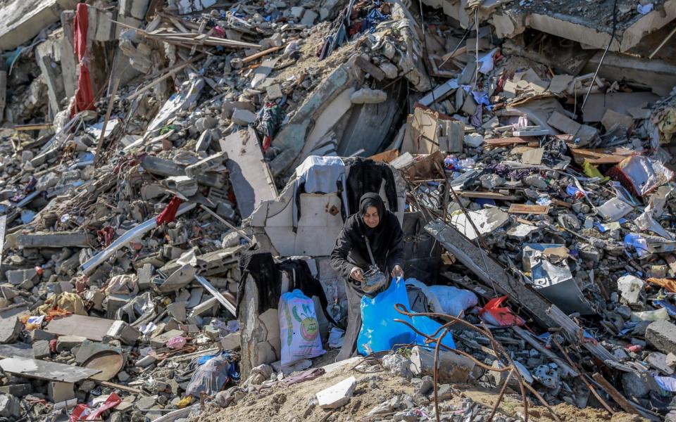 A woman searches for salvageable items on Al-Mukhabarat street in Gaza City