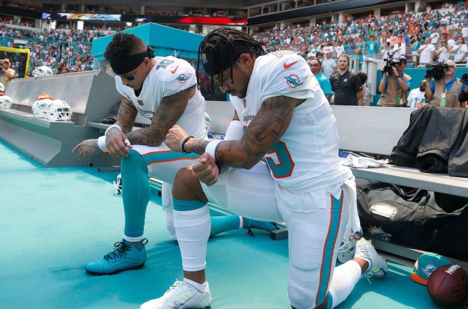 Miami Dolphins players kneel during the national anthem before a game against the Tennessee Titans