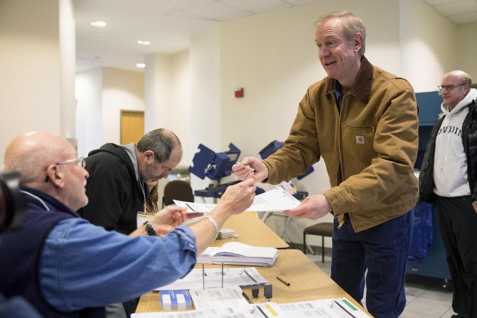 Illinois Republican gubernatorial candidate Bruce Rauner, right, receives his ballot on Tuesday, March 18, 2014, in Winnetka, Ill. Rauner faces State Sen. Bill Brady, State Sen. Kirk Dillard and State Treasurer Dan Rutherford in the primary election. (AP Photo/Andrew A. Nelles)