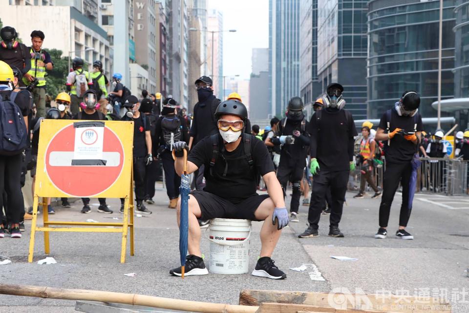 香港「反送中」示威者24日下午在九龍觀塘遊行結束後，轉進包圍附近牛頭角警署；警方發射多輪催淚彈和胡椒球彈驅離，大批抗議者走避，有人眼部受傷送醫。圖為示威者防線前「沈思」。(中央社)