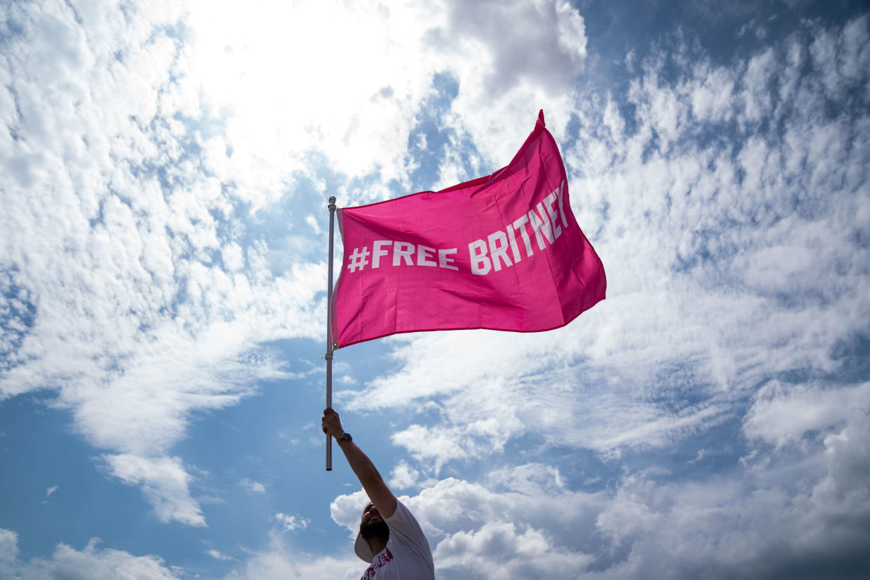 WASHINGTON, DC - JULY 14: Corey Baily, 33, of DC holds a flag as he and other supporters of pop star Britney Spears participates in a #FreeBritney rally near the Lincoln Memorial Reflecting Pool on Wednesday, July 14, 2021. (Kent Nishimura / Los Angeles Times via Getty Images)