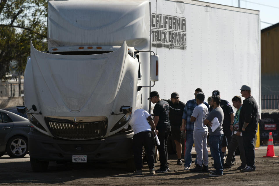 Student drivers gather around a practice truck to inspect the vehicle at California Truck Driving Academy in Inglewood, Calif., Monday, Nov. 15, 2021. Amid a shortage of commercial truck drivers across the U.S., a Southern California truck driving school sees an unprecedented increase in enrollment numbers. The increase is big enough that the school is starting an evening class to meet the demand, according to Tina Singh, owner and academy director of California Truck Driving Academy. "I think that's only going to continue because there's a lot of job opportunities. We have over 100 active jobs on our job board right now," said Singh. The companies that normally would not hire drivers straight out of school are "100 percent" willing to hire them due to shortage issues, the director added. (AP Photo/Jae C. Hong)