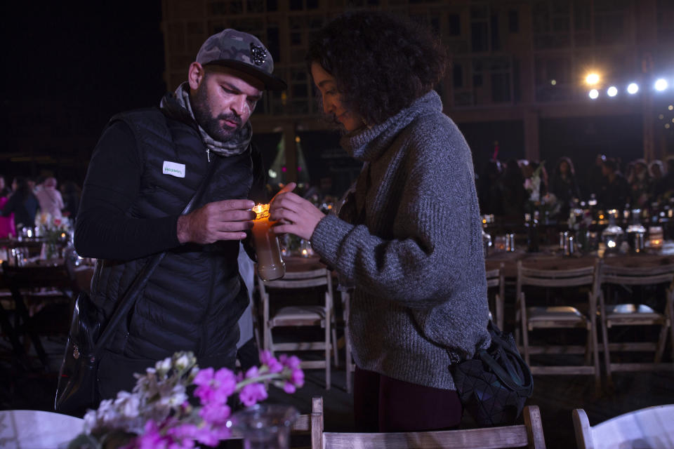 In this Monday, Dec. 23, 2019, photo, volunteers light a candle for a table set for a public Christmas dinner for the needy, at Martyrs Square, where anti-government activists are encamped, in Beirut, Lebanon. Lebanon is entering its third month of protests, the economic pinch is hurting everyone, and the government is paralyzed. So people are resorting to what they've done in previous crises: They rely on each other, not the state. (AP Photo/Maya Alleruzzo)