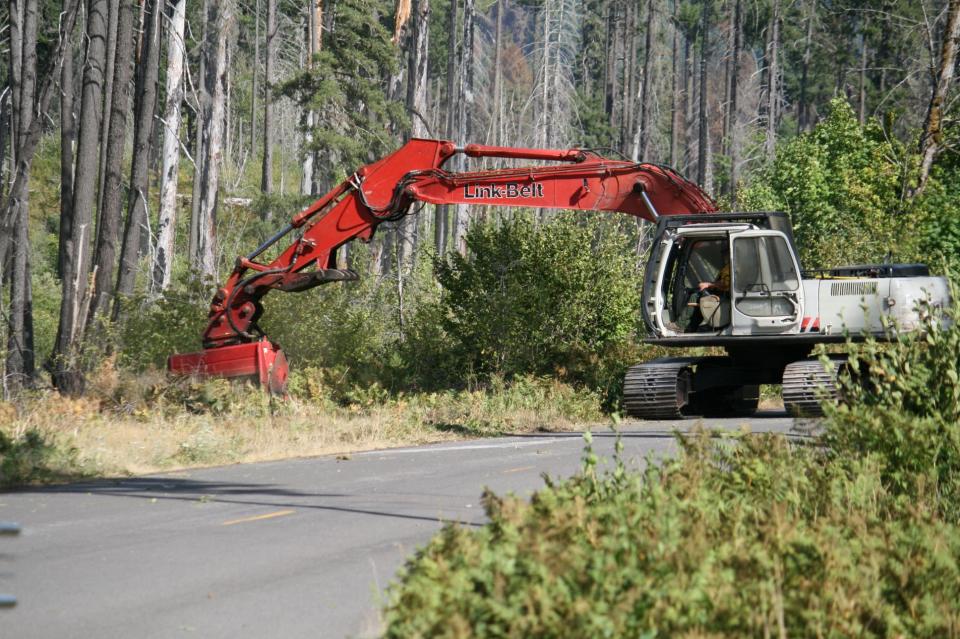 An excavator with a masticator attachment mulches trees and brush in Division Alpha on the Bedrock Fire to expand the fuel break prior to a burnout operation.