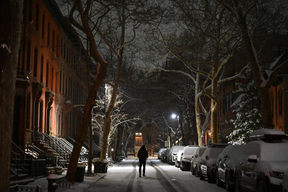 A person walks along a snow-covered street in Brooklyn.