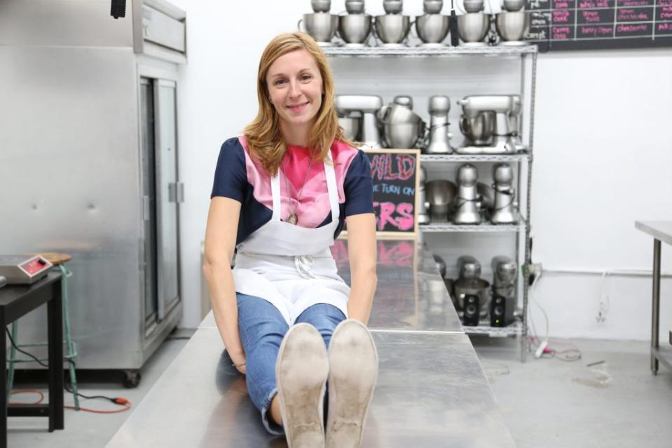Christina Tosi sits on top of a table in her kitchen