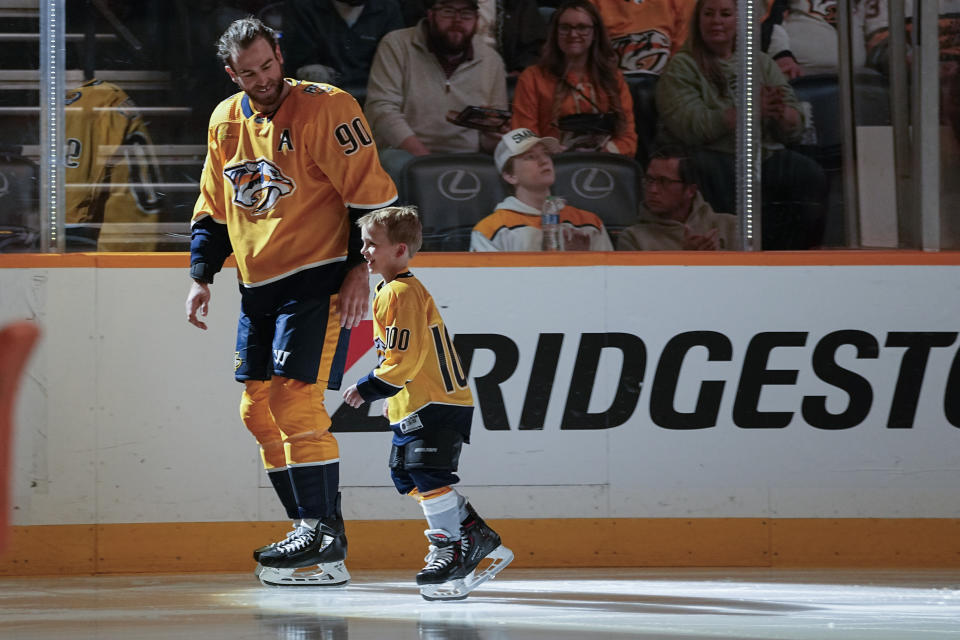 Nashville Predators center Ryan O'Reilly (90) skates with his son, Jameson, before NHL hockey game against the Arizona Coyotes, Saturday, Nov. 11, 2023, in Nashville, Tenn. O'Reilly celebrated his 1,000th game in the league. (AP Photo/George Walker IV)