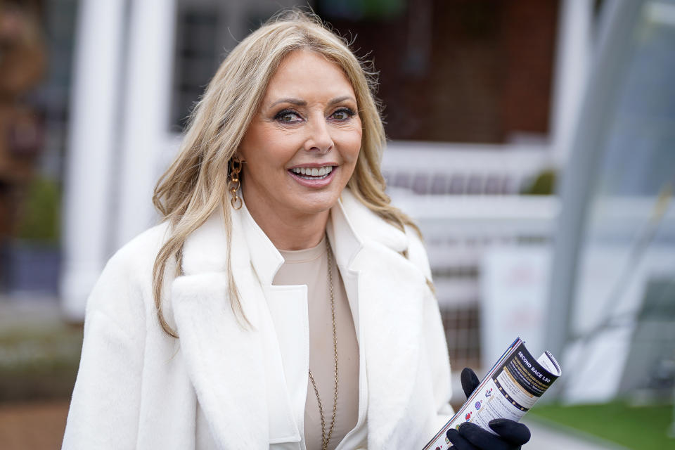 Carol Vorderman, wearing a white coat and light brown top underneath, smiles as she attends the races at Sandown Park Racecourse on March 07, 2023