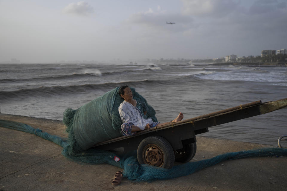 A woman takes rest on a handcart as high tide waves hit the Arabian Sea coast at Juhu Koliwada in Mumbai, India, Monday, June 12, 2023. Cyclone Biparjoy, the first severe cyclone in the Arabian Sea this year is set to hit the coastlines of India and Pakistan Thursday. (AP Photo/Rafiq Maqbool)