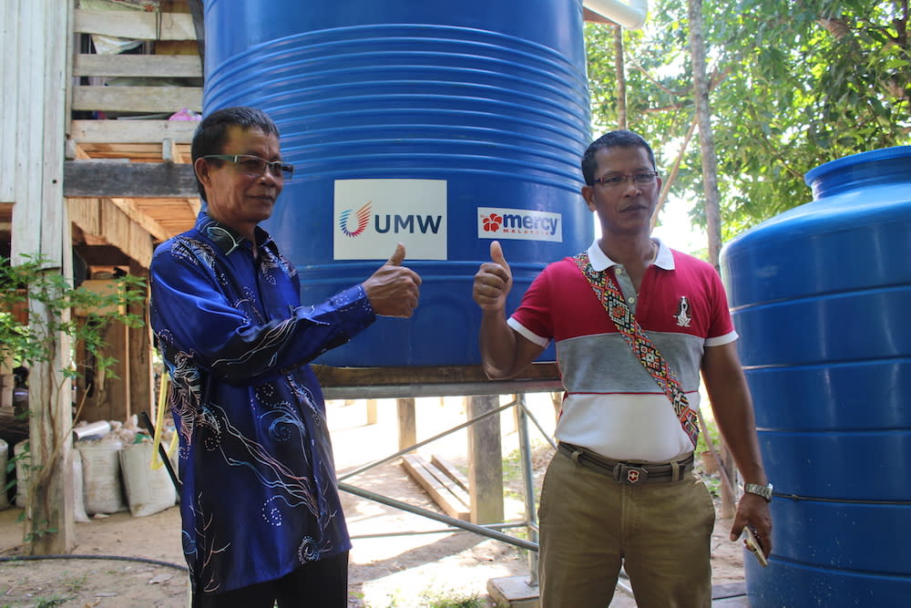 Marius Mokinson (right) and village head Juslee Bokoot with one of the newly installed tanks at a home in Kampung Suang Duyung, Pitas. — Picture by Julia Chan