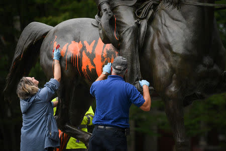 Municipal workers attempt to remove paint from a monument dedicated to Confederate soldier John B. Castleman that was vandalized late Saturday night in Louisville, Kentucky, U.S., August 14, 2017. REUTERS/Bryan Woolston