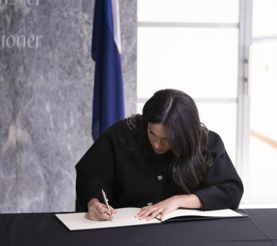 The Duchess of Sussex signs a book of condolence on behalf of the royal family.
