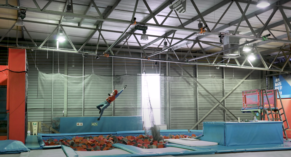 An engineer using his IRL Spider-Man web shooters to swing over a pit of foam cubes.