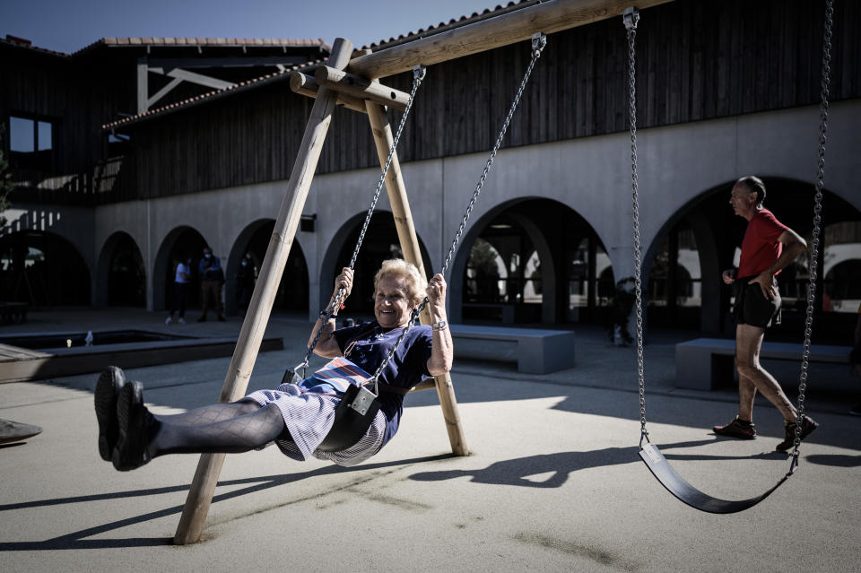 En la imagen, una mujer disfruta en un columpio mientras un hombre pasea tras ella en un parque de una localidad situada al suroeste de Francia en la que todos sus vecinos padecen alzhéimer. (Foto: Philippe Lopez / AFP / Getty Images).