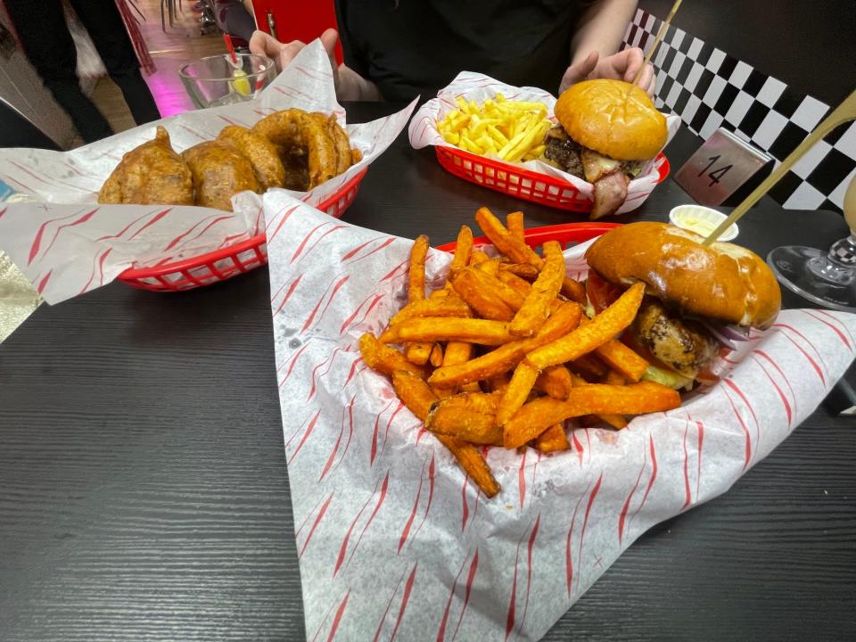 Two burgers and a portion of onion rings at Karen's diner, served in plastic trays