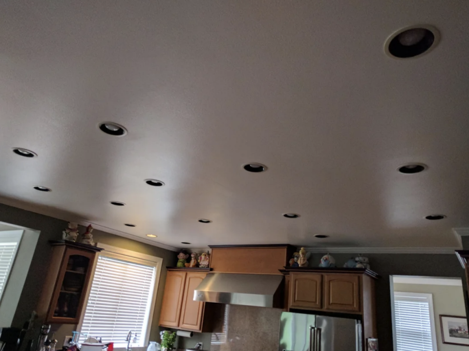 Interior view of a kitchen with recessed lighting and cabinets and some decorations on top