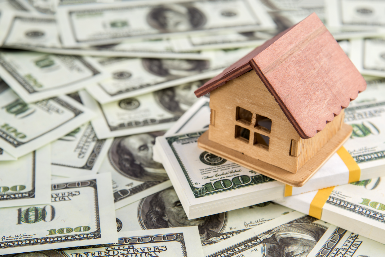 Model home on a stack of money