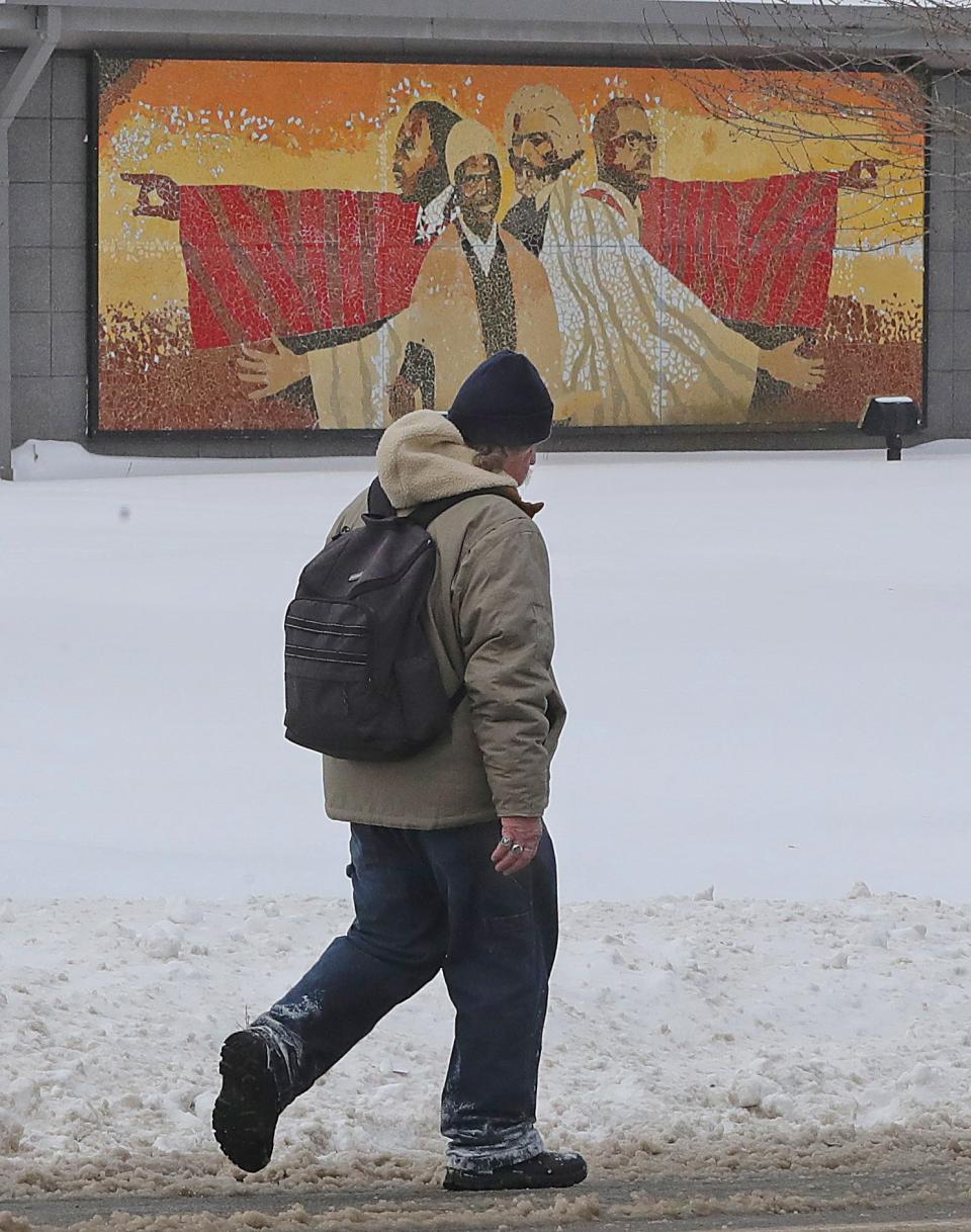 A pedestrian walks along Vernon Odom Boulevard past a mural of Martin Luther King Jr. on Monday, Jan. 17, 2022 in Akron.