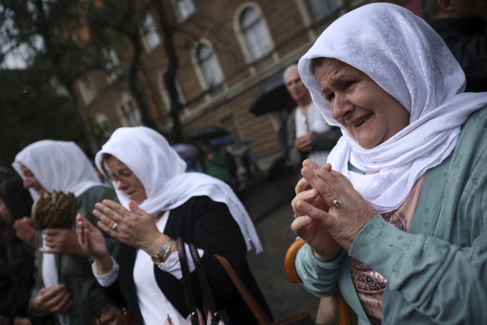 Women pray next to the truck carrying 50 coffins with remains of the victims of the 1995 Srebrenica genocide in Sarajevo, Bosnia, Friday, July 8, 2022. The remains of the 50 recently identified victims of Srebrenica Genocide will be transported to the Memorial centre in Potocari where they will be buried on July 11, the anniversary of the Genocide. (AP Photo/Armin Durgut)