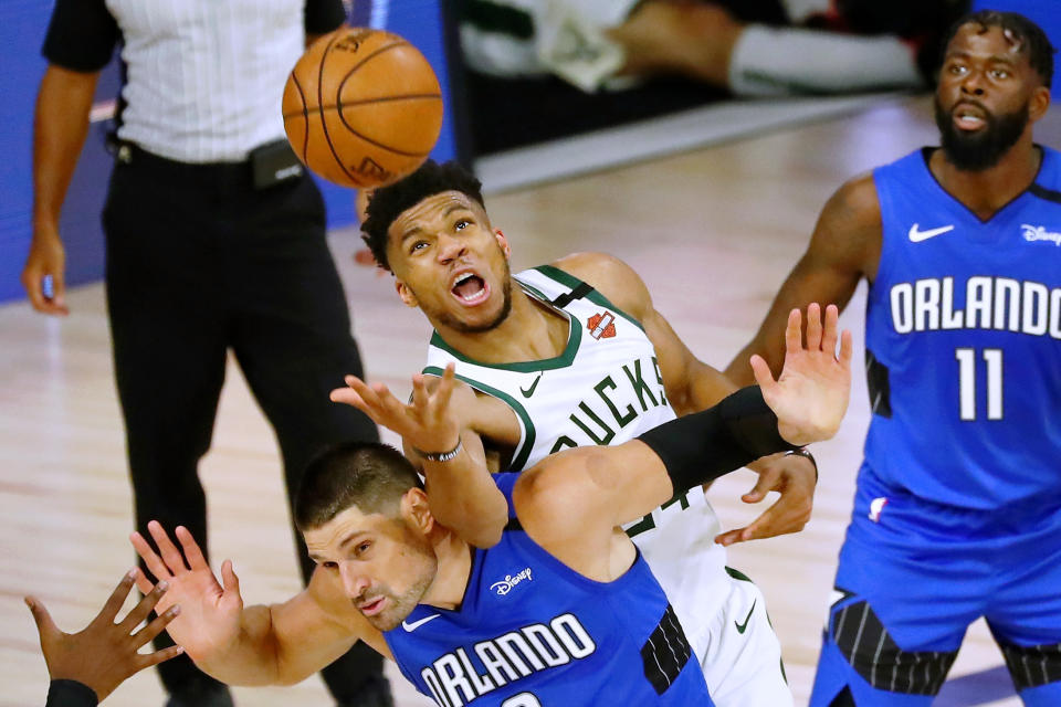 LAKE BUENA VISTA, FLORIDA - AUGUST 18: Giannis Antetokounmpo #34 of the Milwaukee Bucks fouls Nikola Vucevic #9 of the Orlando Magic while reaching for a loose ball in the second half during Game One in the first round of the NBA playoffs at The Field House at ESPN Wide World Of Sports Complex on August 18, 2020 in Lake Buena Vista, Florida. NOTE TO USER: User expressly acknowledges and agrees that, by downloading and/or using this Photograph, user is consenting to the terms and conditions of the Getty Images License Agreement. (Photo by Kim Klement-Pool/Getty Images)