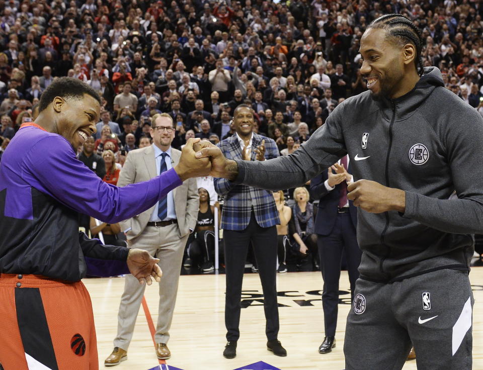 Former Toronto Raptors and now Los Angeles Clippers forward Kawhi Leonard, right, receives his 2019 NBA championship ring from Raptors' Kyle Lowry prior to an NBA basketball game, Wednesday, Dec. 11, 2019, in Toronto. (Nathan Denette/The Canadian Press via AP)