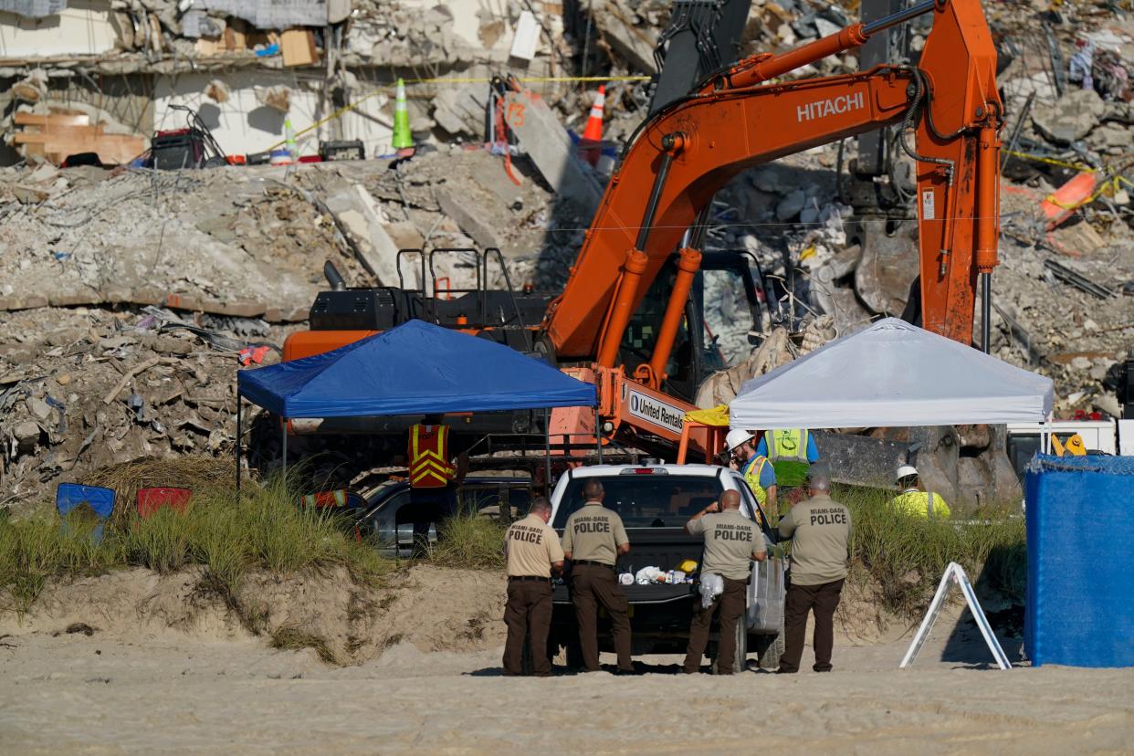 Police watch search and rescue efforts from below the rubble pile at the Champlain Towers South condo building, where scores of people remain missing more than a week after it partially collapsed, Friday, July 2, 2021, in Surfside, Fla.