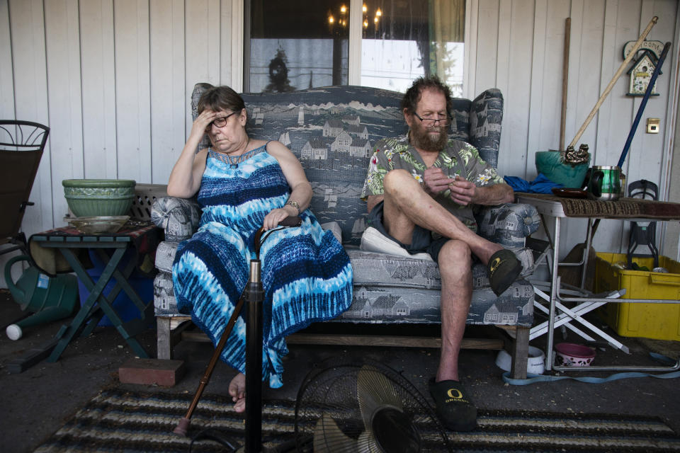 Judy, left, and Merlyn Webber sit out in front of their home at Mobile Estates on Southeast Division Street in Portland, Ore., Tuesday, July 26, 2022. Merlyn Webber, who was struggling with his psoriasis, said he misplaced the tools to fix his fan (shown in the foreground). (Beth Nakamura/The Oregonian via AP)