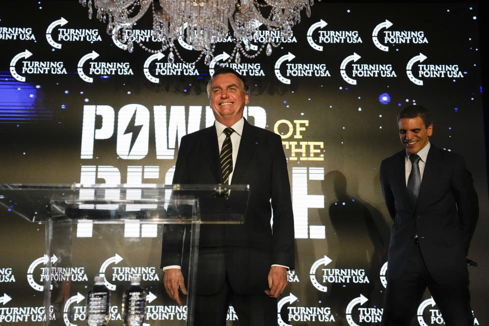 Brazil's right wing former President Jair Bolsonaro stands on stage, flanked by a translator, after speaking at an event hosted by conservative group Turning Point USA, at Trump National Doral Miami, Friday, Feb. 3, 2023, in Doral, Fla. (AP Photo/Rebecca Blackwell)