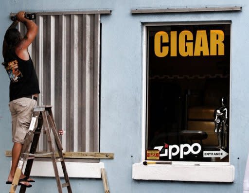 A man installs storm shutters, August 25, in Key West, Florida. Tropical Storm Isaac barreled toward Florida and was predicted to become a hurricane on Sunday, forcing a one-day delay to the Republican convention, after leaving two people dead in Haiti