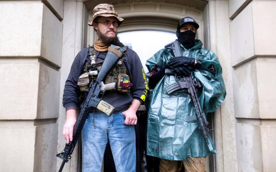 Protesters with long guns shelter from the heavy rain during a protest against Michigan Governor Gretchen Whitmer. - Seth Herald/Reuters