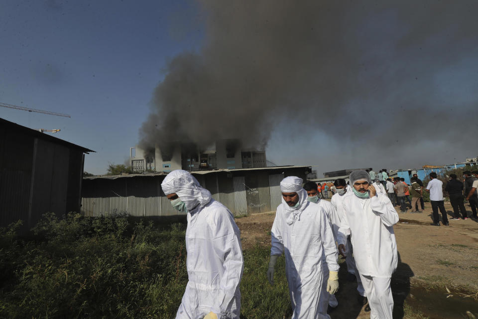Employees leave as smoke rises from a fire at Serum Institute of India, the world's largest vaccine maker that is manufacturing the AstraZeneca/Oxford University vaccine for the coronavirus, in Pune, India, Thursday, Jan. 21, 2021. (AP Photo/Rafiq Maqbool)