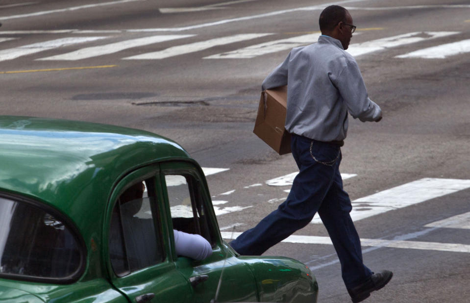 A man runs across a street in front of a slow moving car in Havana, Cuba, Monday, March 4, 2013. Jaywalking is endemic in Havana, where islanders seem to treat the streets like a real-life version of the video game Frogger, weaving in and out of traffic while risking life and limb to reach the other side. Locals call it "toreando autos" _ "bullfighting with cars." (AP Photo/Ramon Espinosa)