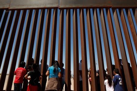 Children interact with members of the Presbyterian church in Sunland Park, U.S. at a new section of the border wall on the U.S.-Mexico border after a liturgy to commemorate the religious dimensions of migration, in this picture taken from Anapra neighborhood in Ciudad Juarez, Mexico May 3, 2018. REUTERS/Jose Luis Gonzalez