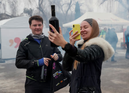 A participant takes a picture of a bottle of wine before the "Milestii Mici Wine Run 2019" race, at a distance of 10 km in the world's largest wine cellars in Milestii Mici, Moldova January 20, 2019. Picture taken January 20, 2019. REUTERS/Gleb Garanich