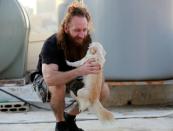 Shady Rizk, a survivor wounded during last year's Beirut port blast, plays with his dog on the rooftop of his house, in Sin el-Fil